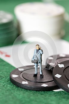 Miniature Businessman standing on a poker chip