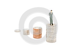 Miniature businessman standing on stack of new Thai Baht coins.