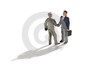 Miniature businessmen shaking hands on white