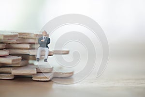 Miniature businessmen sitting on a wood jigsaw puzzle white background copy space