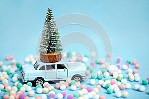 Miniature car carrying a Christmas tree on blue background