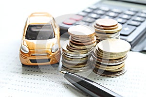 Miniature car model, coins stack, calculator and saving account book or financial statement on office desk table