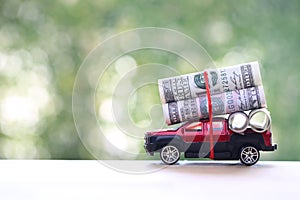 Miniature car and usd dollar money on nature green background, Saving money for car, Finance and car loan, Investment and business