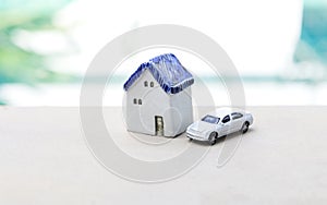 Miniature ceramic house with model car over blurred blue swimming pool background