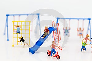 Miniature children: The boy is playing slider happily with friend on playground. Image use for Children`s Day.