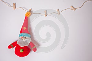 Miniature Christmas funny toy Santa hanging on the clothes pin on a white background