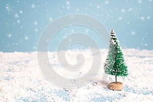 Miniature Christmas Tree with snowfall. Copy space for text. Holiday and celebration concept.