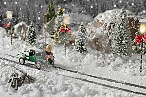Miniature classic car carrying a christmas tree on snowy road on winter