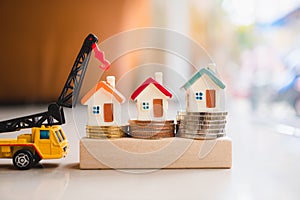 Miniature colorful house on stack coins with construction vehicle using as business, property and finance concept