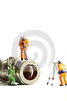 Miniature construction workers plumbing valve