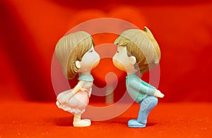 The Miniature Couple dolls Boy and Girl Romantic Kiss on Red Heart Background for valentine`s Day Concept