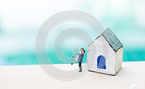 Miniature couple and wooden house model over blurred background, handmade miniature house for small garden decoration