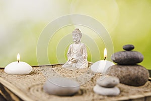 Miniature desk zen sandbox with Buddha figure sit in Lotus position, stacked zen sea stones, spa candles .