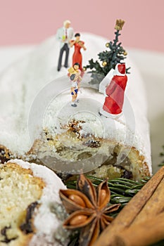 A miniature family is celebrating christmas on a christmas stollen with a little christmas tree and santa clause