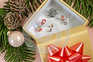 A miniature family is celebrating christmas in a gift box while santa claus is joining them with presents