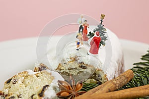 A miniature family is celebrating christmas on top of an powdered fruit cake