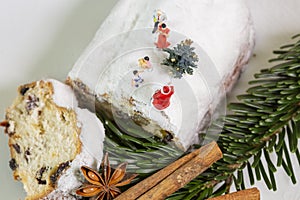 A miniature family is celebreting christmas on an powdered christmas stollen