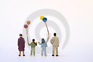 Miniature family with children and colorful balloons - white background, copy space