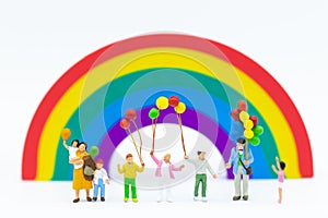 Miniature family: Children holding balloon with rainbow for background. Image use for international children`s day