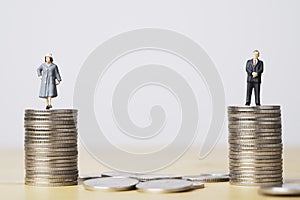 Miniature figure of businessman standing on equal coins stacking of  businesswoman for equality of gender male and female of