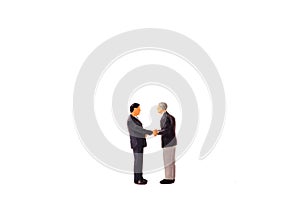 Miniature figure businessmen handshaking on white background