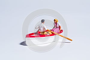 Miniature figure concept of couple rowing the boat