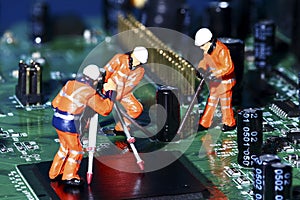 miniature figure workmen on an electronic circuit board