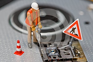 Miniature figures working on a DVD drive.