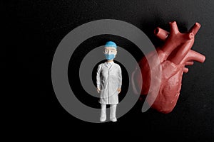 Miniature figurine of a cardiologist doctor with a giant heart on a black background photo