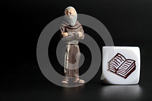 Miniature figurine of a friar with a symbol of a book on a black background
