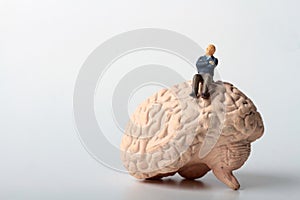 Miniature figurine of a man sitting on a giant brain