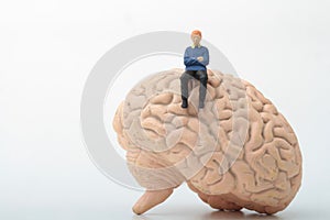 Miniature figurine of a man sitting on a giant brain
