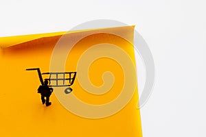 Miniature figurine posed as businessman looking at shopping cart handrawn on adhesive paper note photo