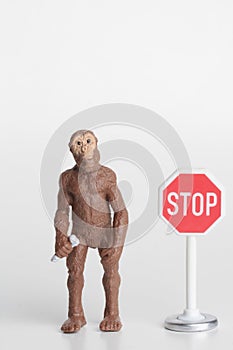 Miniature figurine of a prehistoric hominid with a stop sign