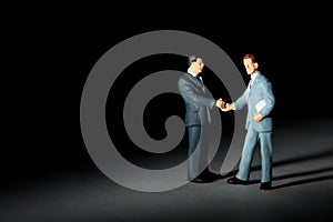 Miniature figurines of handshaking businessmen