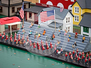 Miniature figurines marching band in parade with on lookers with US flag