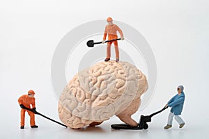 Miniature figurines of men at work with a giant brain