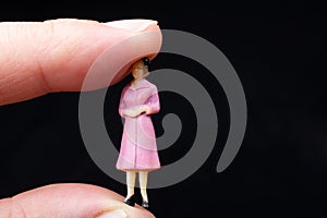 miniature figurines of a woman sitting betwee the finger of a hand