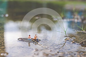 Miniature fishermen are fishing by boat