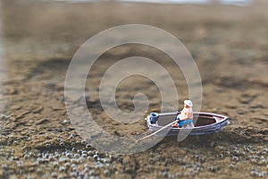 Miniature fishermen are fishing by boat