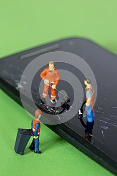 Miniature garbage man recycling and cleaning an broken smartphone
