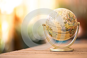 Miniature globe model on a rustic wooden table. Symbol for travelling