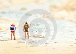 Miniature Group traveler with backpack standing on wold map for travel around the world.
