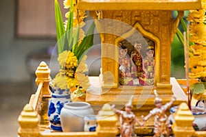 Miniature guardian spirit house. Small buddhist temple shrine, colorful flower garlands. San phra phum erected to bring fortune.