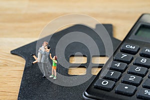 Miniature happy family figure standing on paper house with calculater as property or financial investment plan concept