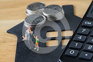 Miniature happy family figure standing on paper house with calculator as mortgage or financial investment plan concept