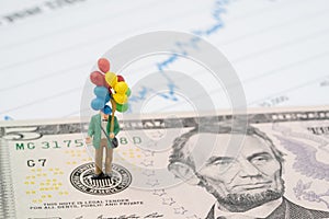 Miniature happy man holding colorful balloons on US Federal Reserve emblem on US dollars banknote as FED consider interest rate