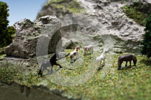 Miniature horse plastic toy model. Herd of horses grazing in the meadow on the mountain hillside.