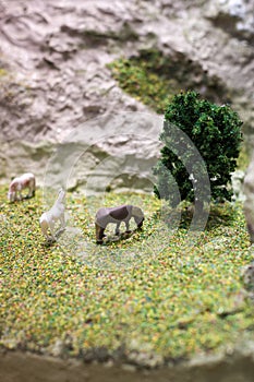 Miniature horse plastic toy model. Herd of horses grazing in the meadow on the mountain hillside.