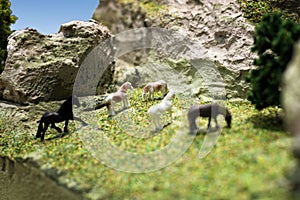 Miniature horse plastic toy model. Herd of horses grazing in the meadow on the mountain hillside.